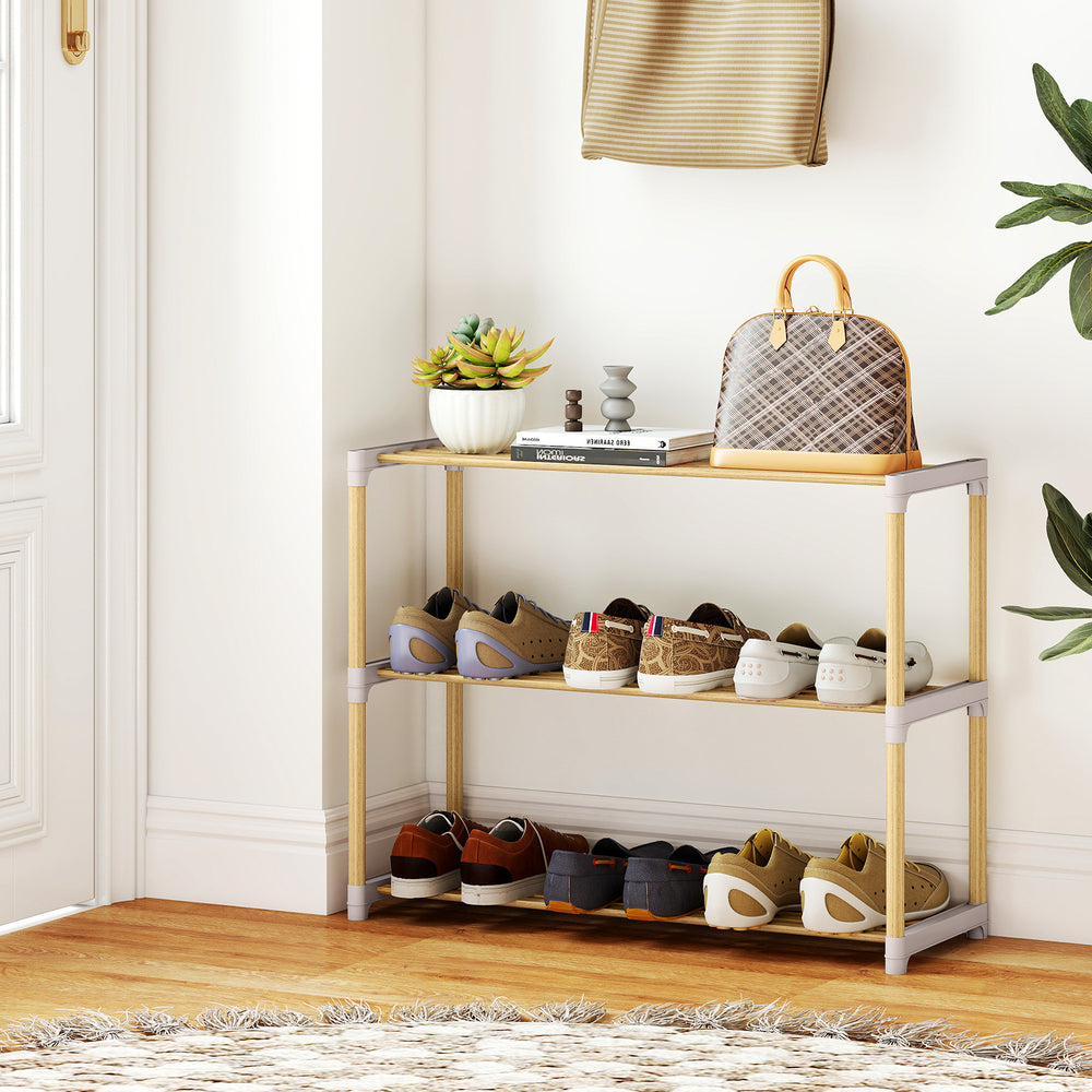 Three-tier solid wood shoe rack with slatted open shelves, showcasing shoes and a stylish natural wood finish in an.