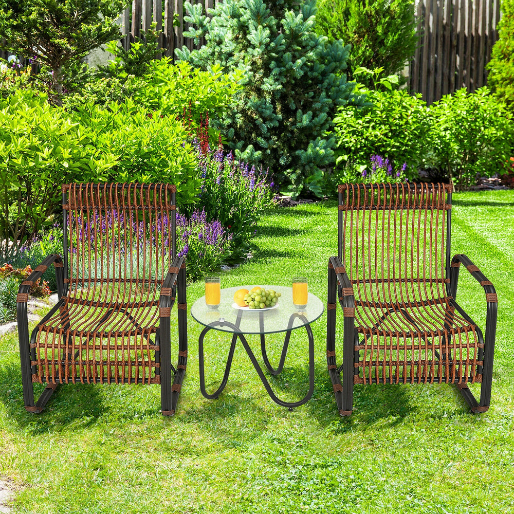 Two single wicker chairs with a glass side table in a garden, perfect for outdoor patio relaxation.