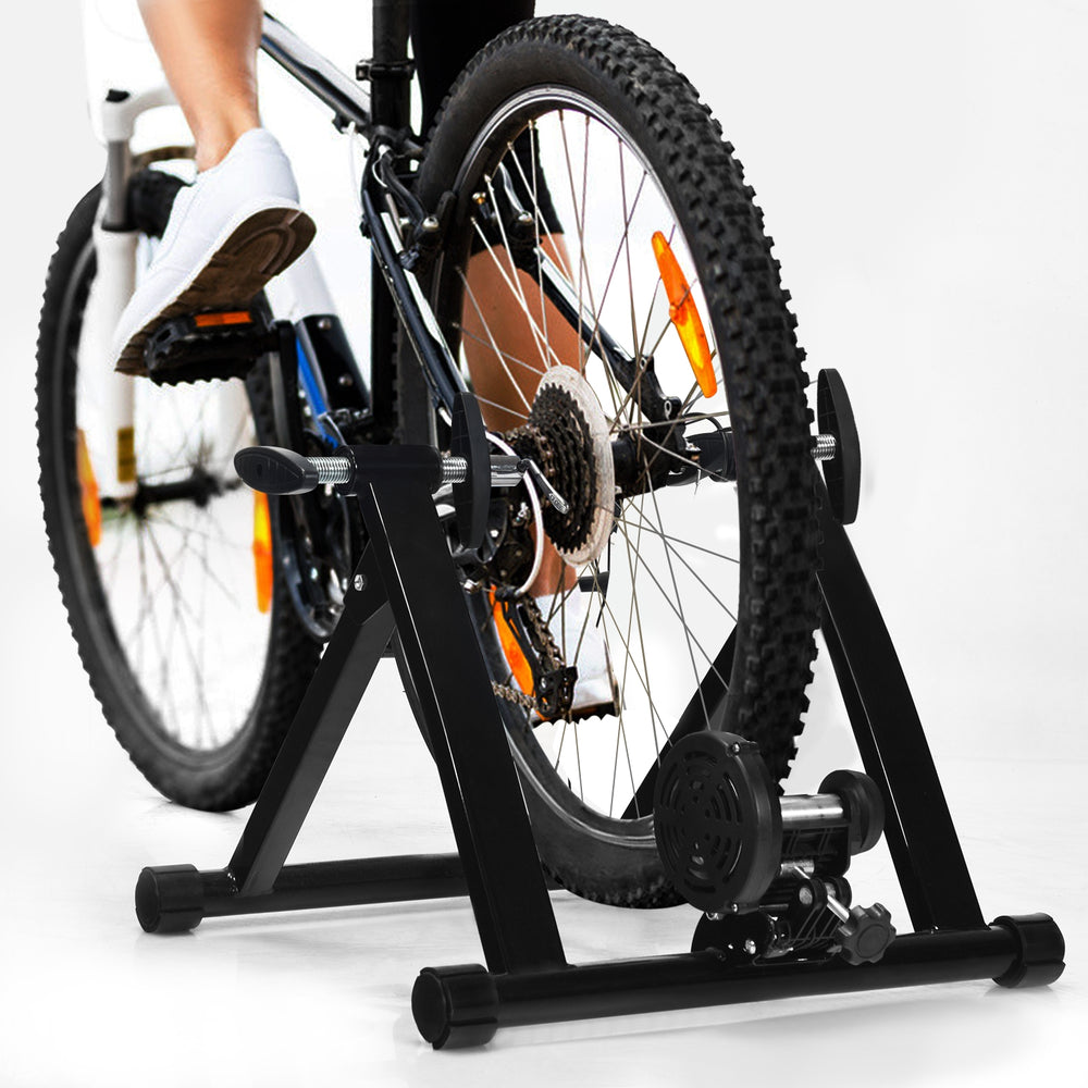 Portable folding steel bicycle indoor exercise training stand with a pyramid structure, suitable for 26"-28" wheels.