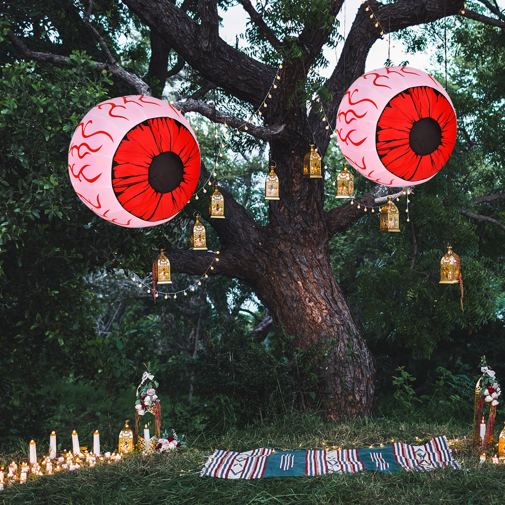 Two inflatable Halloween eyeballs with red LED lights, creating a spooky atmosphere in a festive outdoor setting.