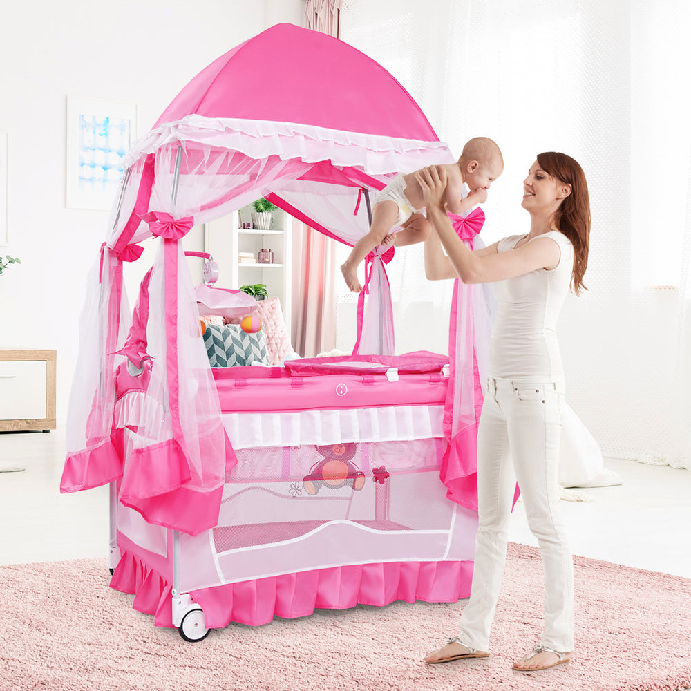 Portable pink baby playpen crib with diaper changing pad and mosquito net, ideal for safe naps and playtime.