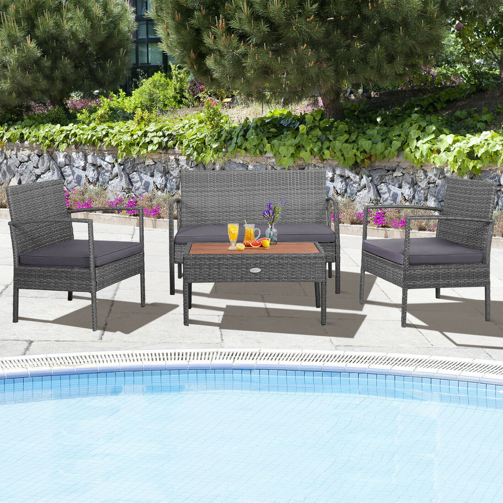 4-piece rattan patio conversation set featuring acacia wood tabletop, ideal for poolside relaxation with soft cushions.