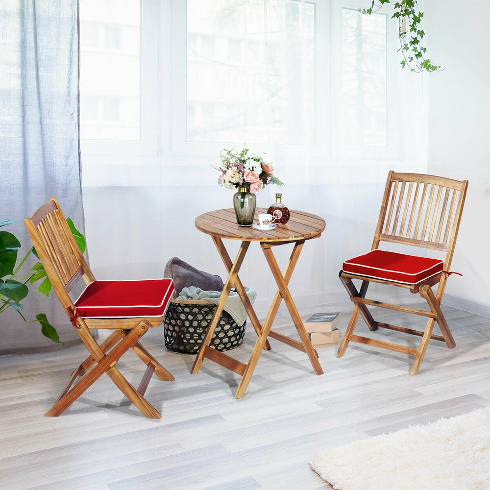 Folding bistro set featuring solid acacia wood chairs with red padded cushions and a round coffee table for outdoor use.