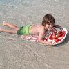 Child enjoying the 41-inch lightweight surfboard with a floral design in shallow water, perfect for summer fun.