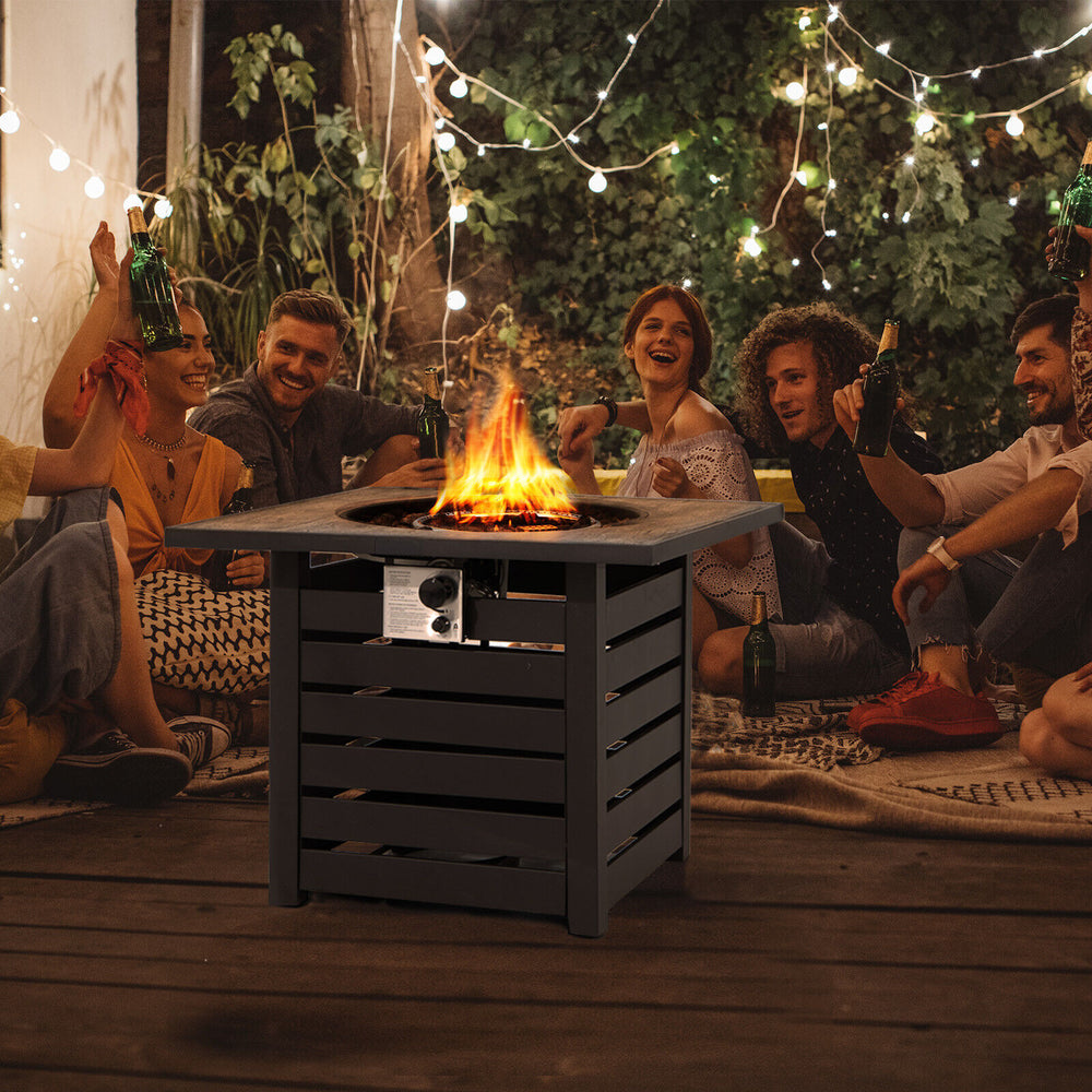 Square propane fire pit table with lava rocks, ideal for outdoor gatherings on patio or poolside, featuring a rain.