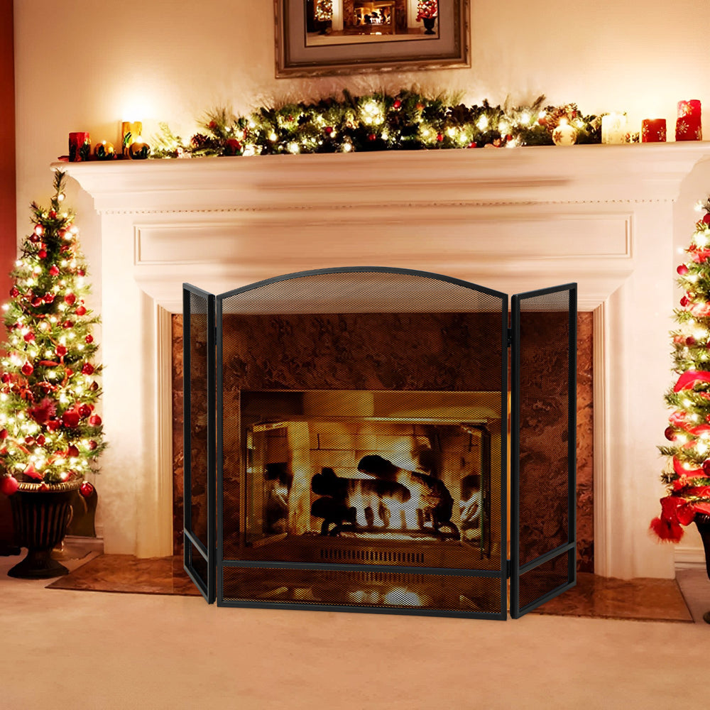 Three-panel foldable fireplace screen in black wrought iron, providing safety from sparks in a cozy living room setting.