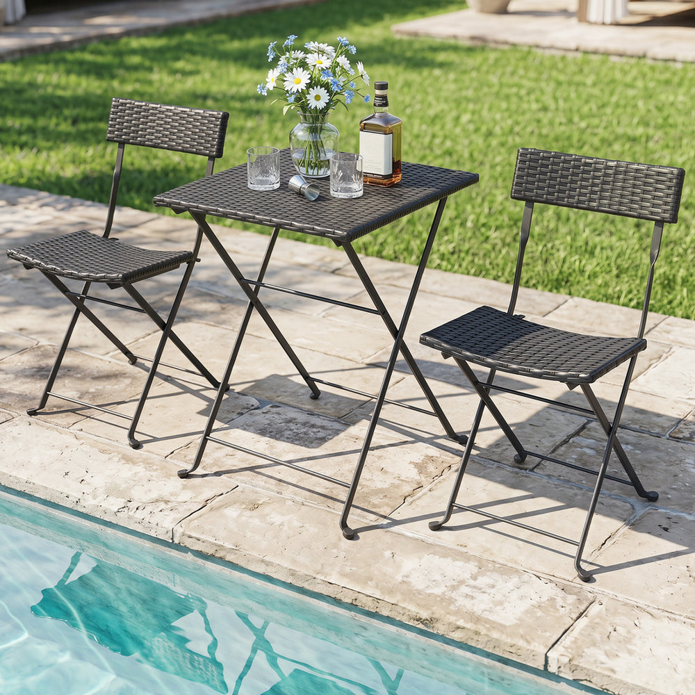 Folding bistro set with black PE wicker and X-shaped metal frame, perfect for outdoor use by the poolside or patio.