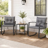 Two gray rocking chairs with thick cushions and a glass-top table create a relaxing outdoor conversation space.