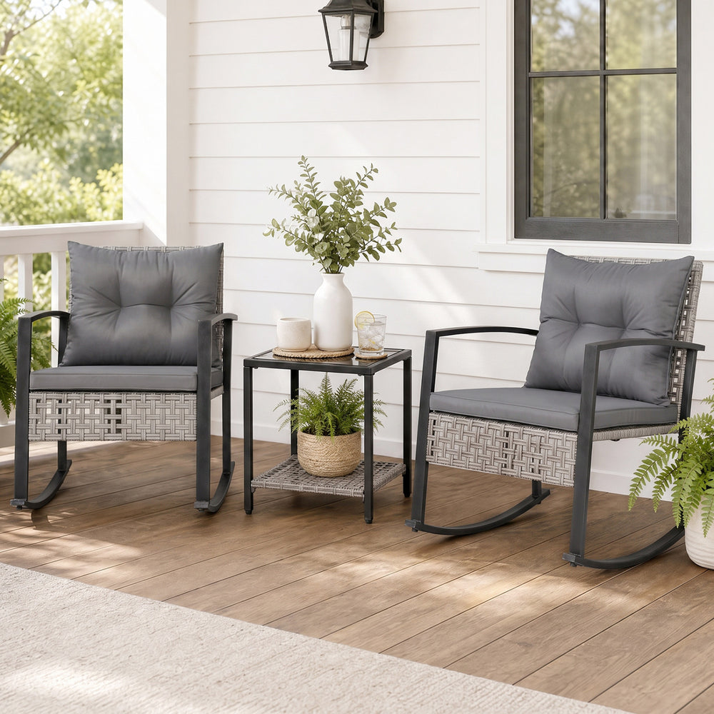 Two gray rocking chairs with thick cushions and a glass-top table create a relaxing outdoor conversation space.