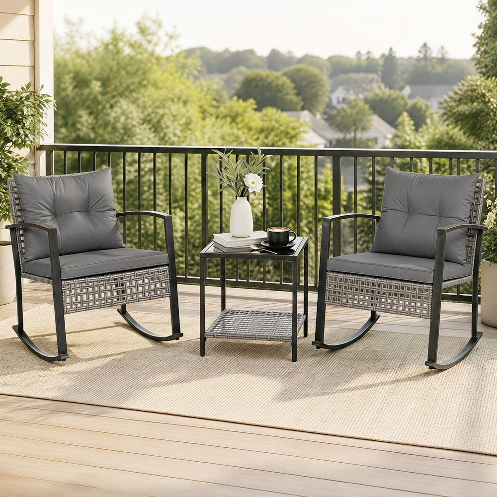 Two gray rocking chairs with plush cushions and a glass-top table create a relaxing outdoor conversation space.