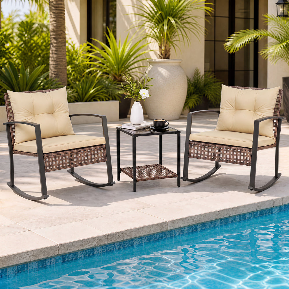 Two brown rocking chairs with thick cushions and a glass-top table create a relaxing outdoor conversation space.