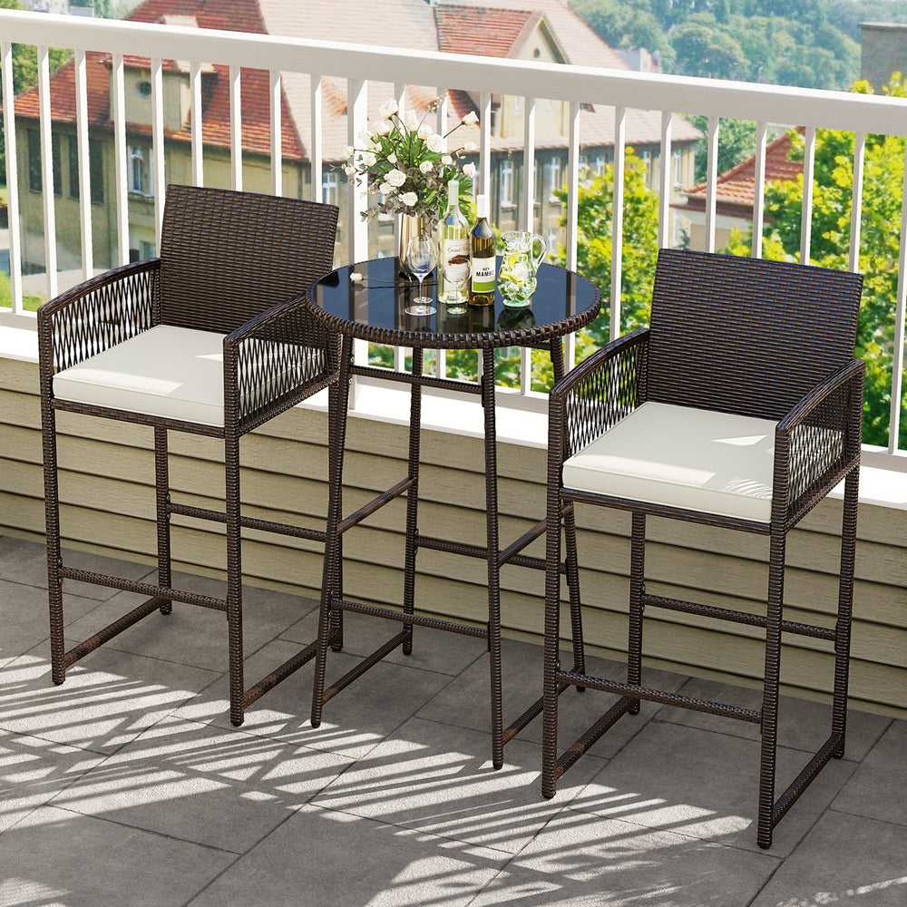 Bar height table and two armchairs in brown PE wicker with white cushions, perfect for outdoor patio relaxation.
