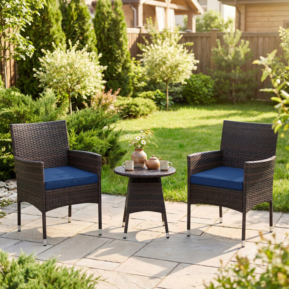 Two navy cushioned chairs and a round table in a garden, featuring brown PE rattan for outdoor patio relaxation.