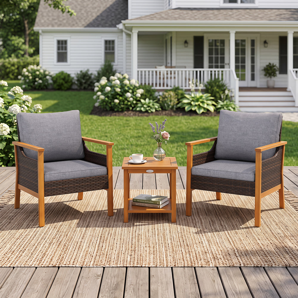 Two gray cushioned patio chairs with a slatted side table, made of acacia wood and PE rattan, perfect for outdoor relaxation.