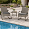 The 3-piece wicker rocking bistro set includes two gray cushioned chairs and a two-tier coffee table for outdoor relaxation.