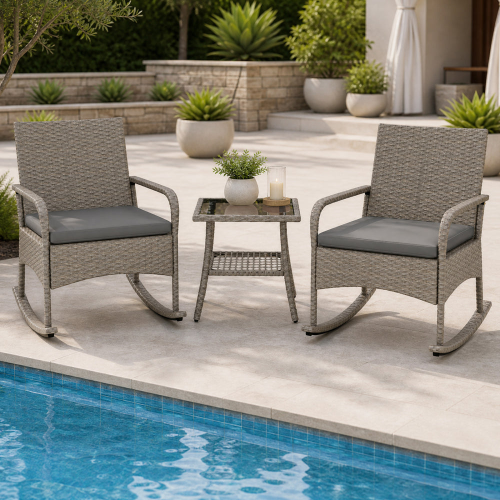 The 3-piece wicker rocking bistro set includes two gray cushioned chairs and a two-tier coffee table for outdoor relaxation.