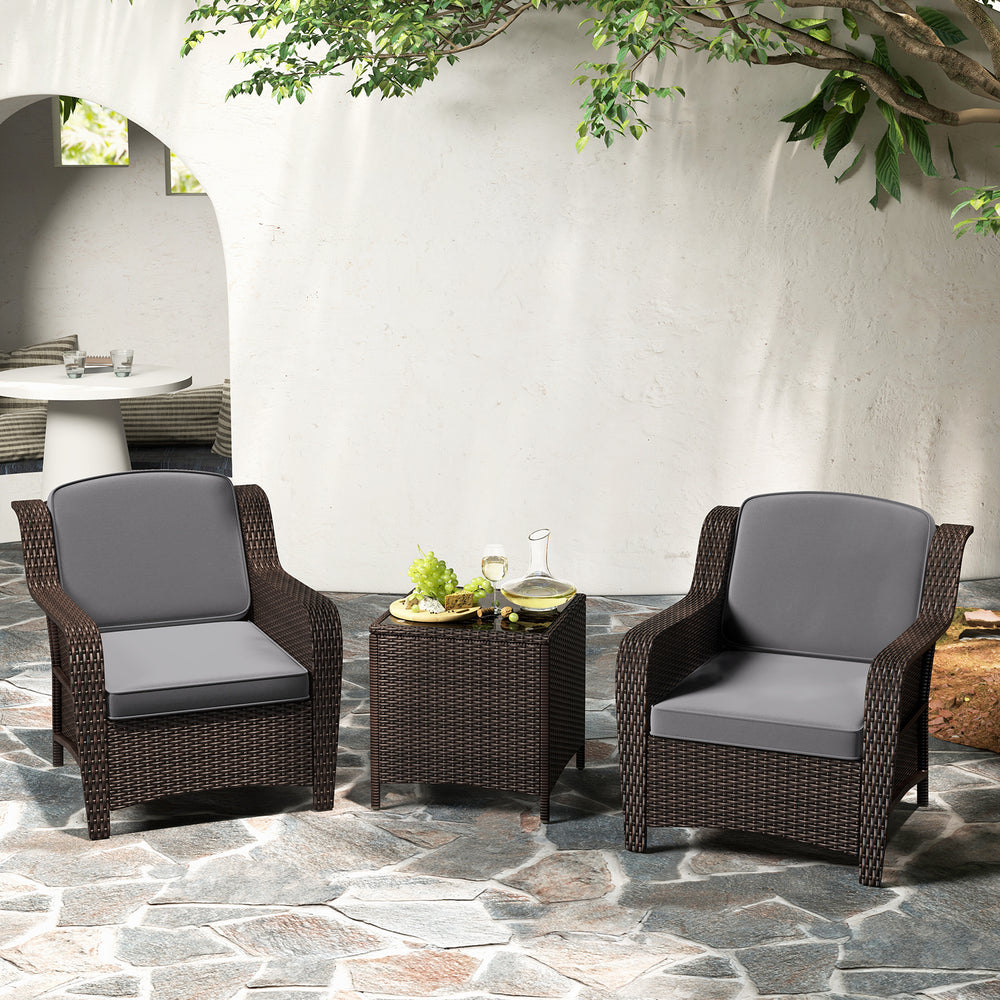 Outdoor rattan furniture set with gray cushions, featuring a tempered glass coffee table, perfect for garden relaxation.