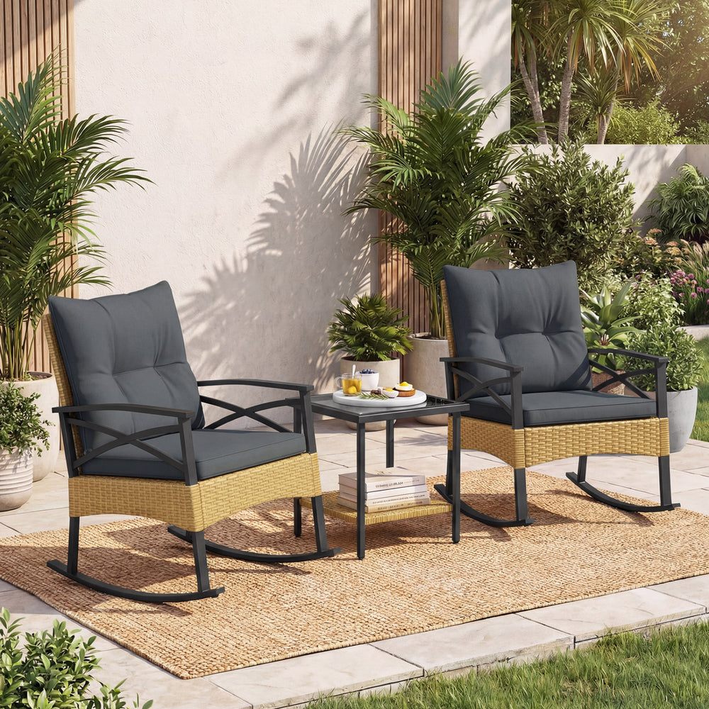 Two gray rocking chairs with thick cushions and a side table, made of PE rattan, perfect for garden relaxation.