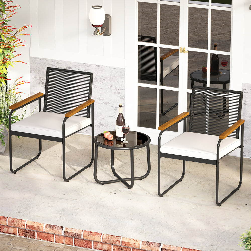 Two patio chairs with white cushions and acacia wood armrests beside a round glass-top table, perfect for outdoor.