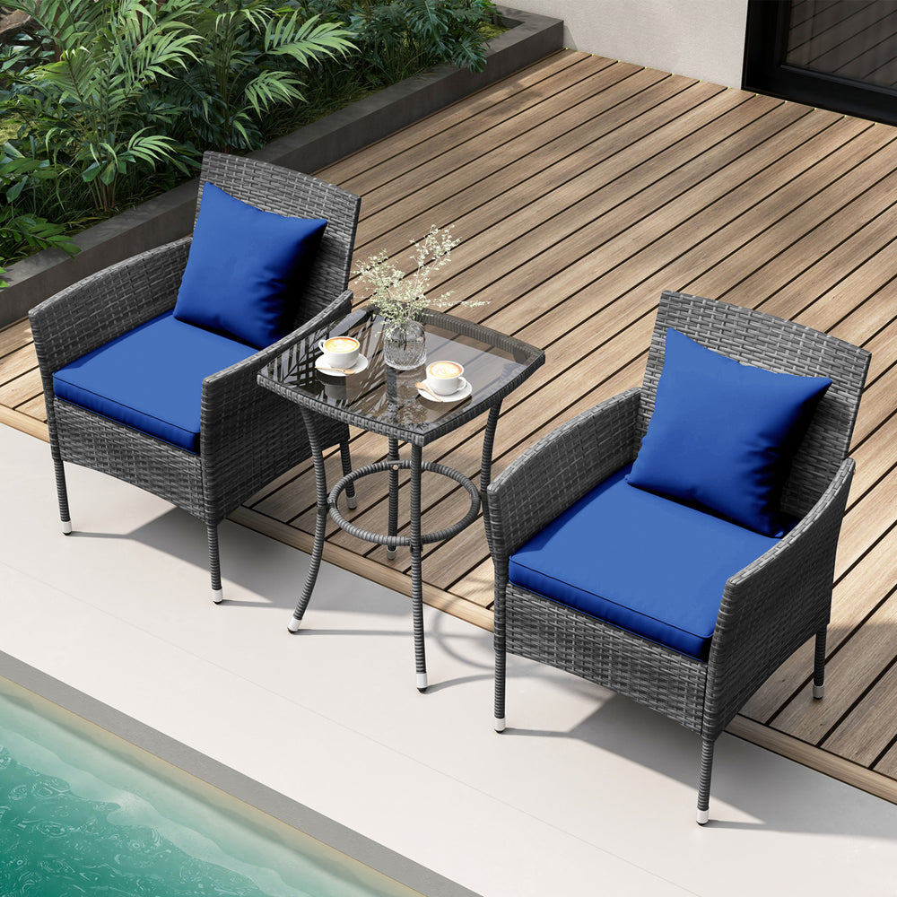 Cushioned patio chairs with navy blue cushions and tempered glass coffee table on a wooden deck by the pool.