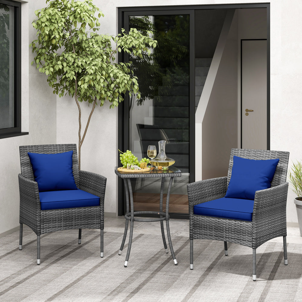Cushioned patio chairs with navy covers and a tempered glass coffee table in a stylish outdoor setting.