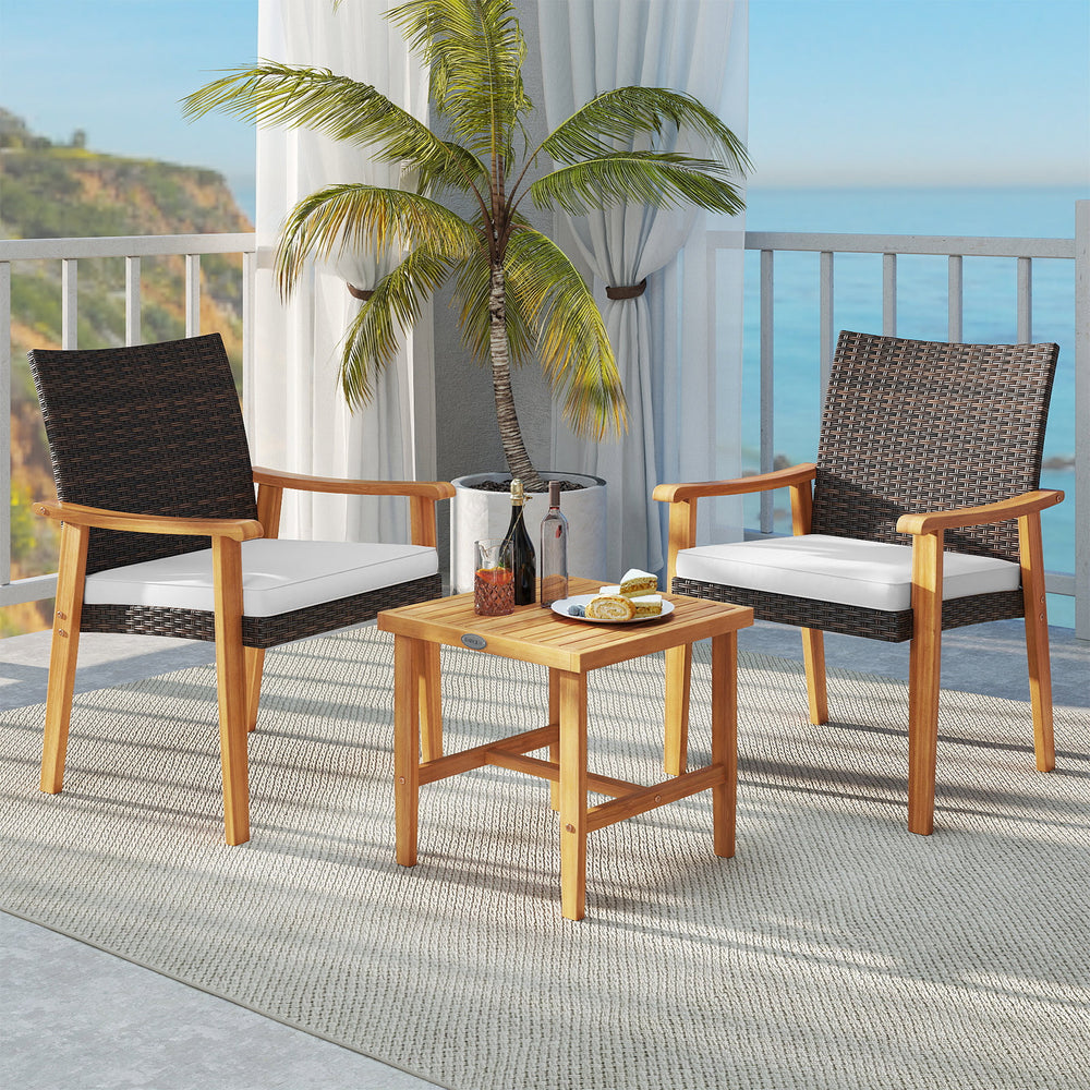Patio bistro set featuring two acacia wood chairs with white cushions and a square coffee table, ideal for outdoor.