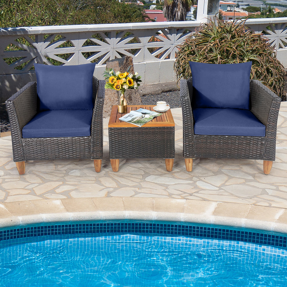 Two navy cushioned rattan chairs with a wooden table, perfect for poolside relaxation in outdoor spaces.