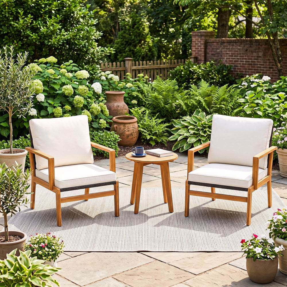 Two acacia wood chairs with off-white cushions and a side table create a cozy outdoor seating area for relaxation.