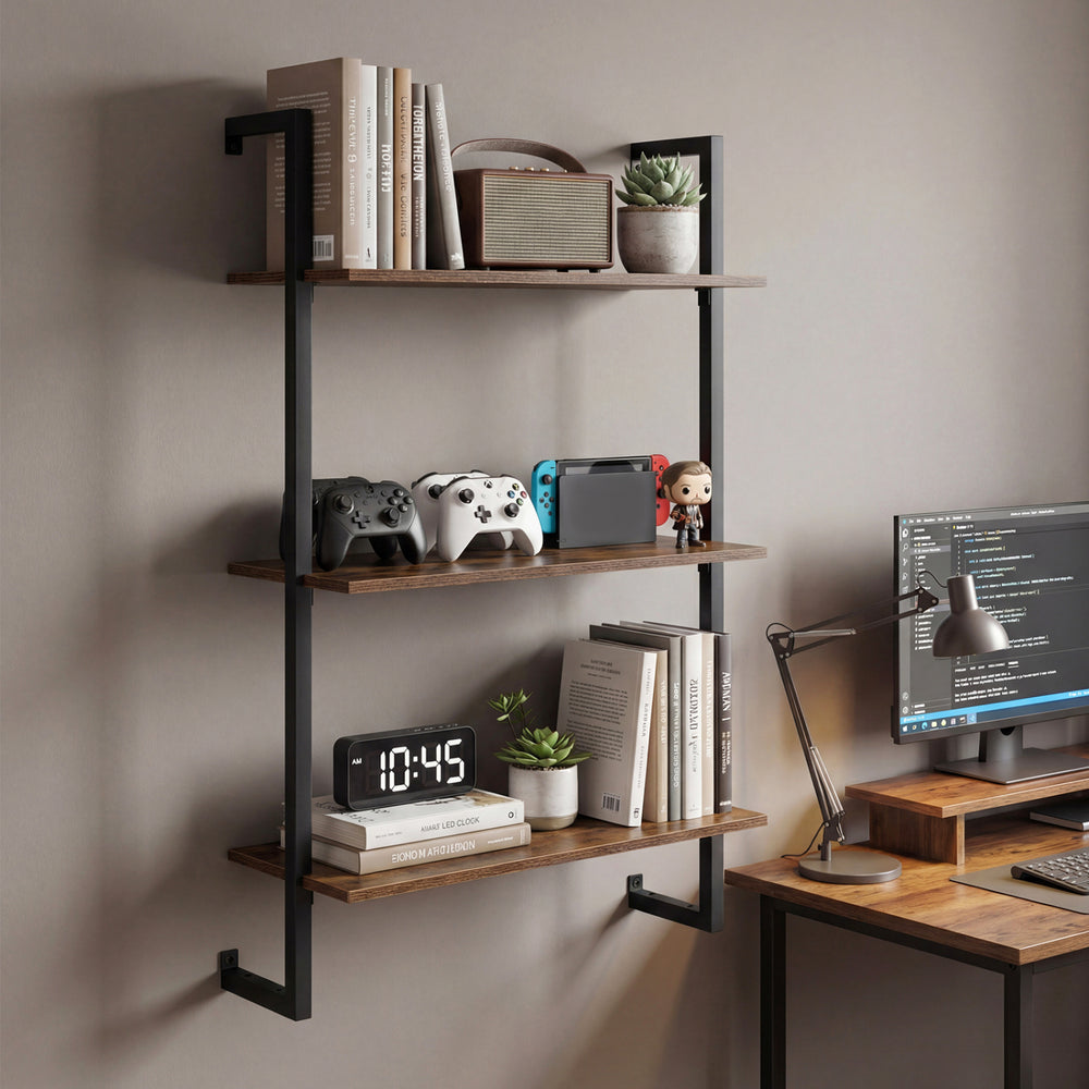 3-tier floating shelf in rustic brown, showcasing books, plants, and gaming consoles, ideal for home office or living.