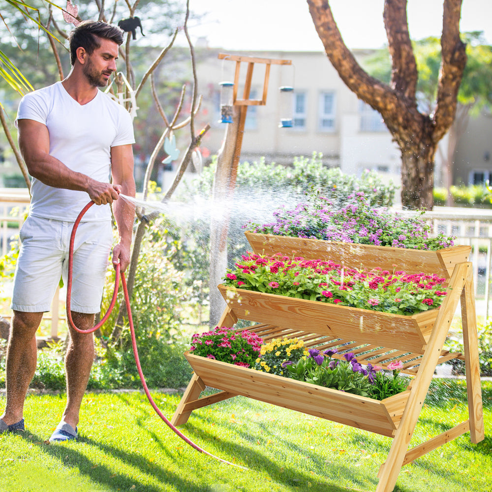 Three-tier wooden vertical raised garden bed with flowers, designed for efficient space use and healthy plant growth.
