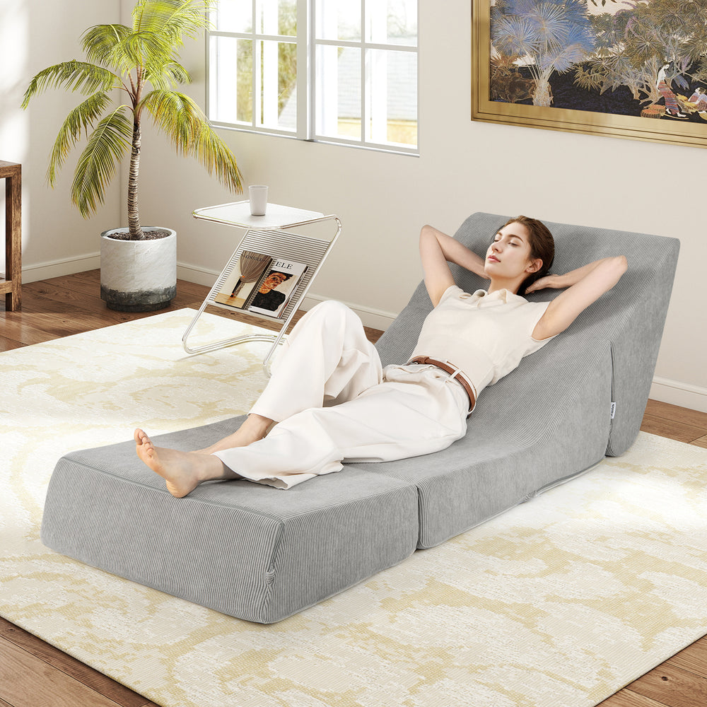 Gray 3-in-1 folding sofa bed with a relaxed user reclining, showcasing the cozy inclined backrest and corduroy cover.