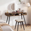 Mid-century modern writing desk in rustic brown with metal legs and drawers, styled with cosmetics and a round mirror.