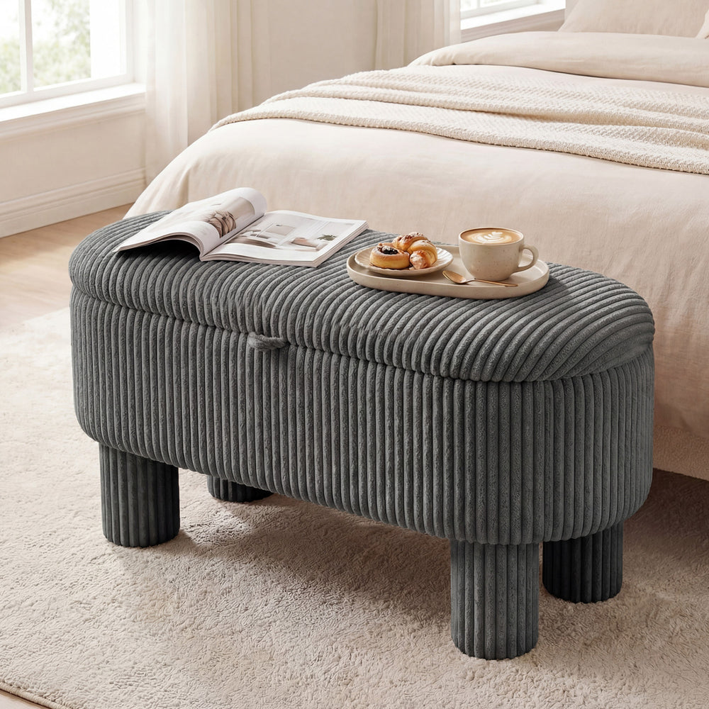 Gray corduroy storage ottoman bench featuring plush upholstery and a convenient lifting strap, perfect for stylish home.