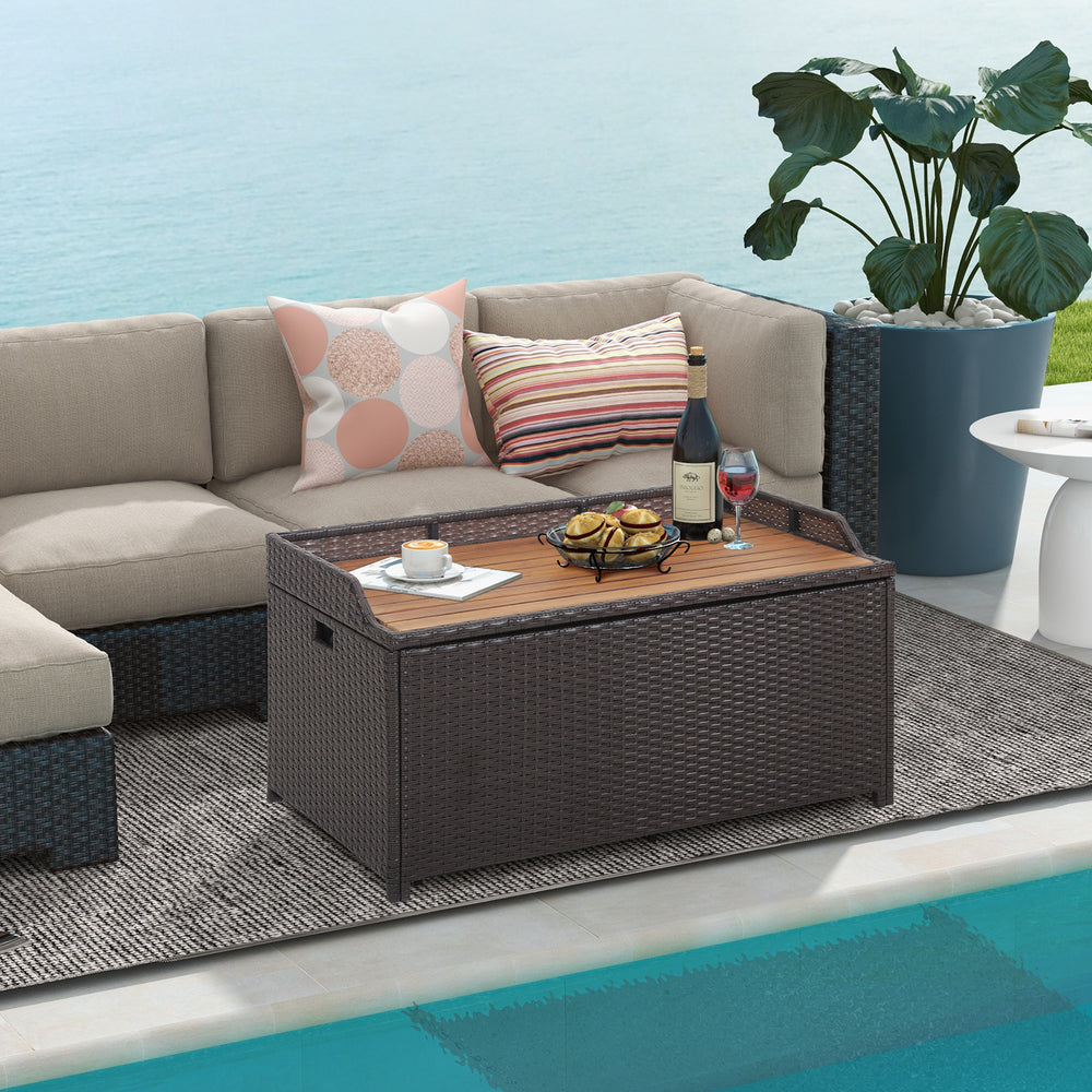 Outdoor storage bench with acacia wood lid, 45-gallon capacity, used as a coffee table beside patio sofa.