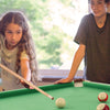 Children playing on a 47-inch green folding billiard table, enhancing hand-eye coordination with cues and accessories.