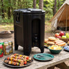 Black insulated beverage dispenser with ergonomic handles, perfect for camping and outdoor parties, showcasing food and.