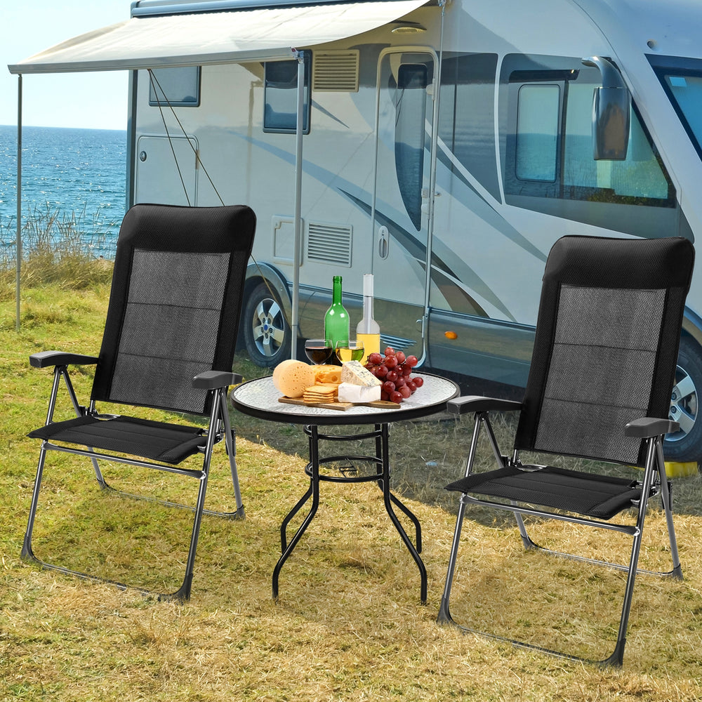 Two portable black patio folding dining chairs with adjustable headrests, set up for outdoor dining by a camper.