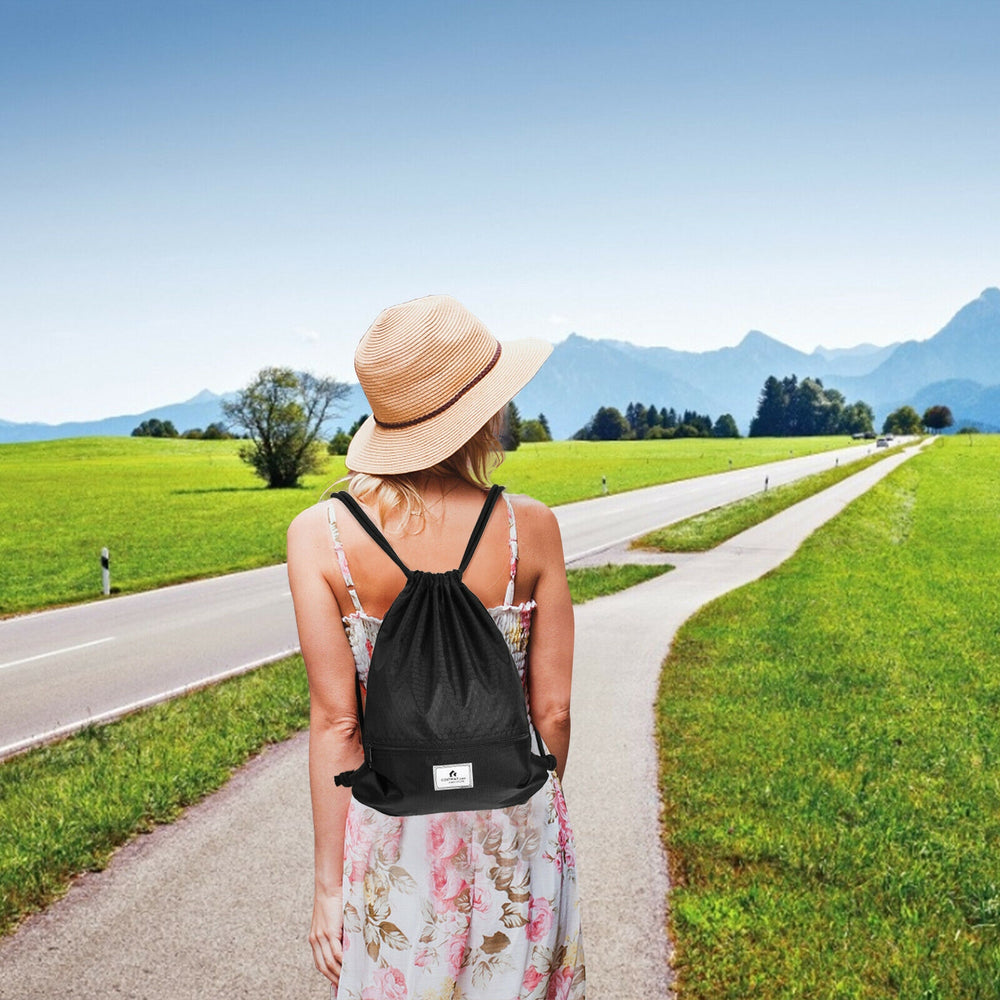 Drawstring backpack in black with zipper pockets, ideal for gym, yoga, and travel, shown against a scenic outdoor.