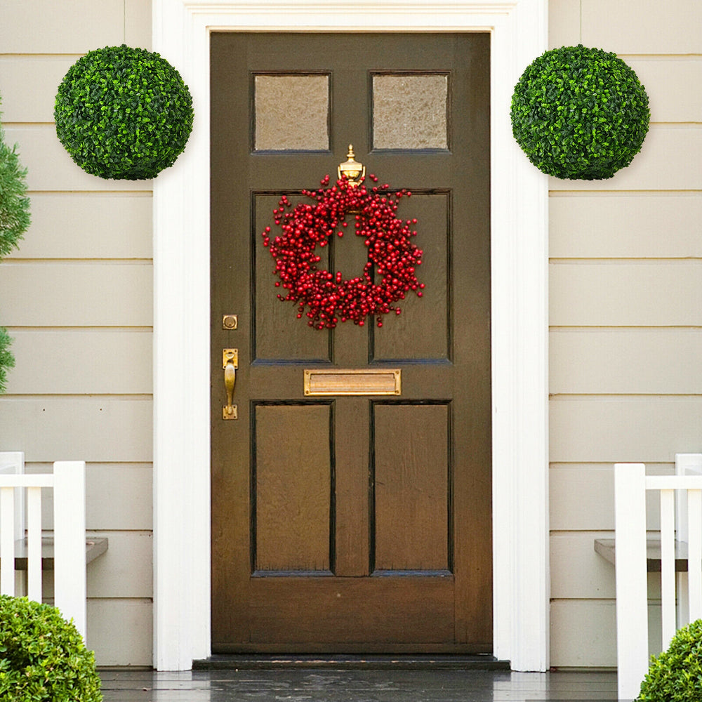 Two 15.7-inch artificial boxwood topiary balls mounted on a door, enhancing the entrance with a realistic green look.