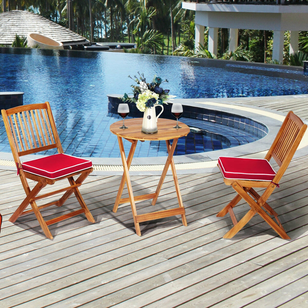 Patio folding bistro set with red padded cushions and round acacia wood coffee table, perfect for outdoor relaxation.
