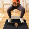 Balance board trainer in black for core strength exercises, featuring birch wood and cork for durability and stability.