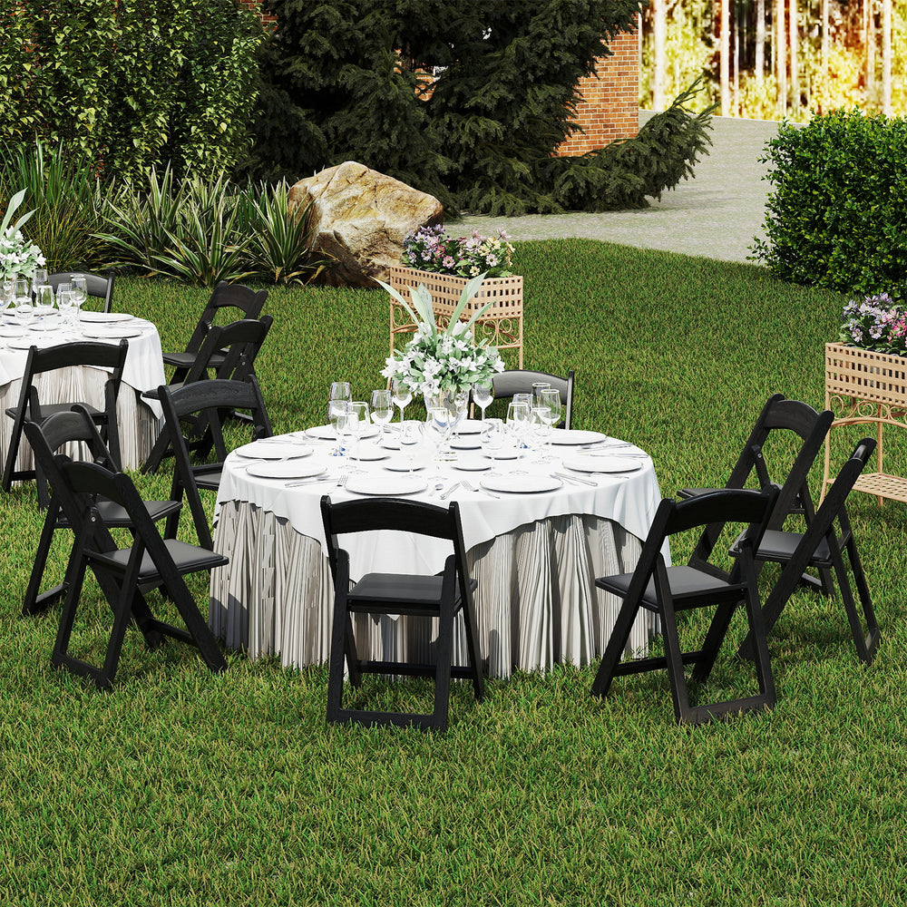 Black resin folding chairs with padded seats arranged around a table, perfect for weddings and outdoor events.