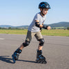 Youth in blue adjustable roller skates with light-up wheels, showcasing safety gear on a smooth outdoor surface.