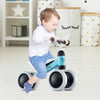 Toddler riding a blue baby balance bike with 4 wheels, designed for stability and motor skills development.