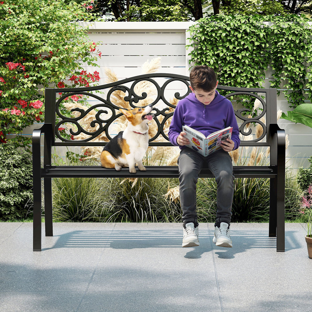 Outdoor cast iron metal patio bench with floral design, providing a cozy spot for 2-3 people in a garden setting.