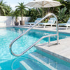 Stainless steel pool handrail with a curved design, mounted on a concrete step for secure entry and exit from the pool.