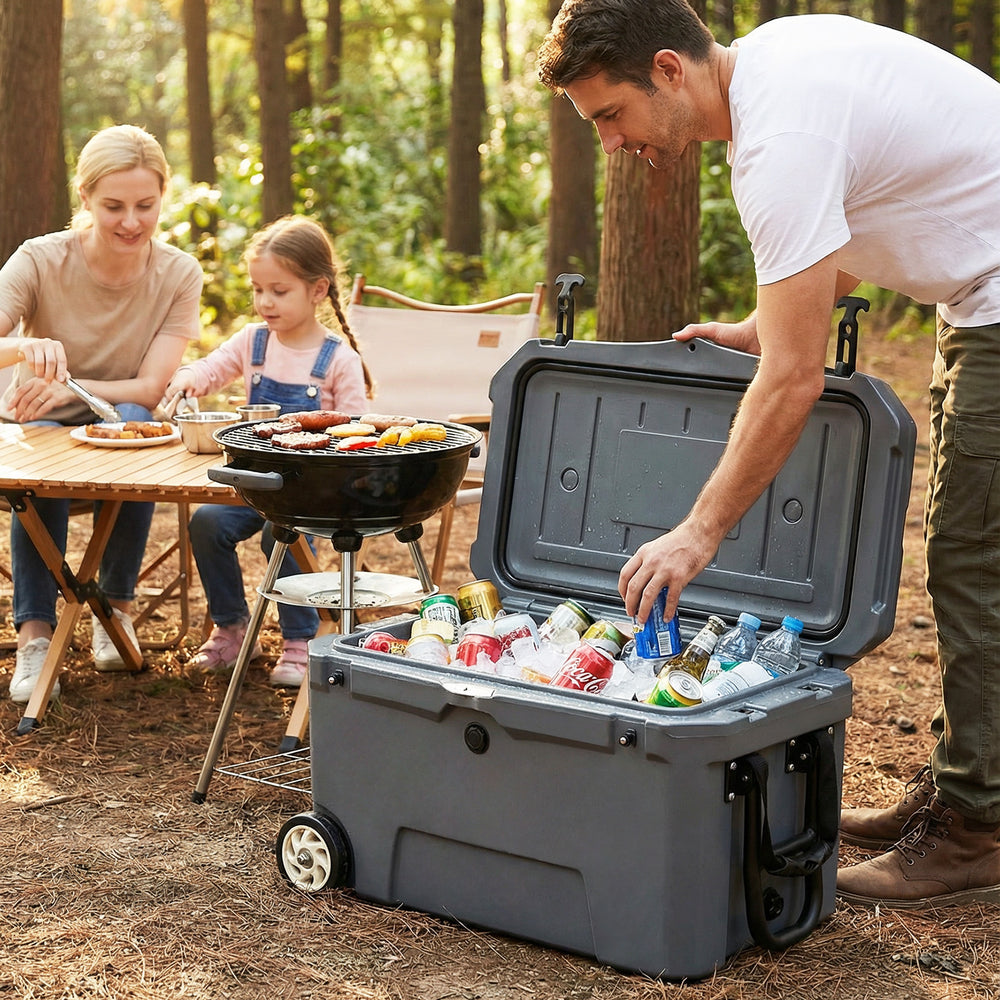 Portable 52 quart gray hard cooler with wheels, filled with drinks, ideal for camping and outdoor barbecues.