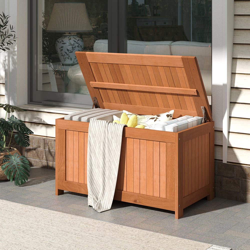 Patio wood deck box with flip top, 52-gallon capacity, ideal for cushions and outdoor storage, shown in a garden.