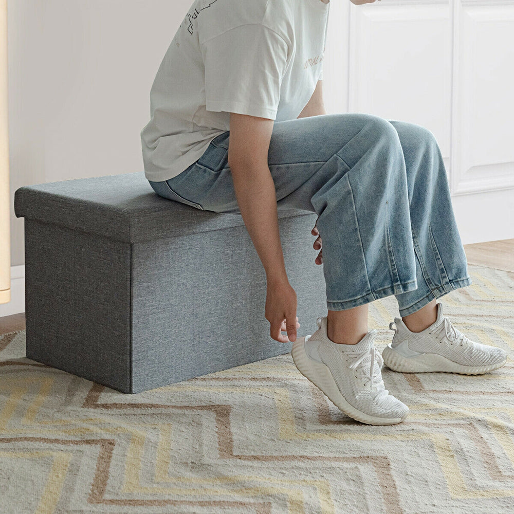 Light gray 30-inch folding storage ottoman with lift top, featuring soft fabric and roomy interior for versatile.