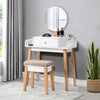 Wooden makeup dressing table set with drawer, round mirror, and cushioned stool, perfect for organizing beauty items.